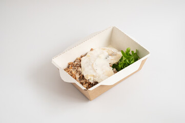 Takeout meals served in biodegradable containers, buckwheat with chicken, garnished with greens.