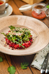 Beetroot salad with arugula in a plate, cafe, restaurant, wooden table.
