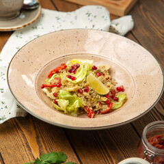 Quinoa salad with pomegranate seeds, cherry tomatoes and lemon in a plate, cafe, restaurant, wooden table. 