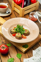 Fried champignons dish with walnut sauce and arugula in a plate, cafe, restaurant, wooden table. Vertical photo