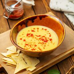 Cheese soup with paprika and corn chips in a plate, cafe, restaurant, on a wooden table.