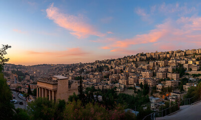 Obraz premium A panoramic view of a city skyline at sunset with a pink and orange sky, with buildings and trees.