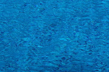 Bright blue water rippling in a calm environment with reflections on the surface during sunlight