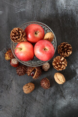 Seasonal composition with chestnuts, red juicy apples and nuts on gray background with space for text. Harvest festival concept. 