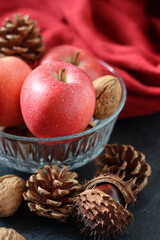 Seasonal composition with chestnuts, red juicy apples and nuts on gray background with space for text. Harvest festival concept. 