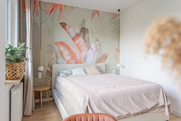 Modern bedroom with textured wallpaper with pattern of leaves. Design interior of room with pillow and comfortable bed. New apartment. Stylish house.	