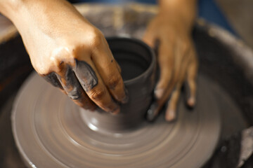 Hands of craftsman artist working on pottery wheel