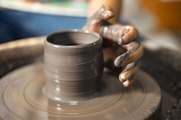 Hands of craftsman artist working on pottery wheel