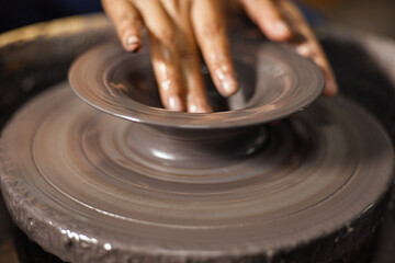 Hands of craftsman artist working on pottery wheel
