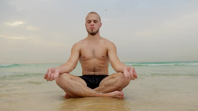 man doing yoga on the beach by the sea