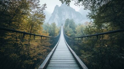 Fototapeta premium Suspension Bridge Leading Through Misty Forest to Mountains