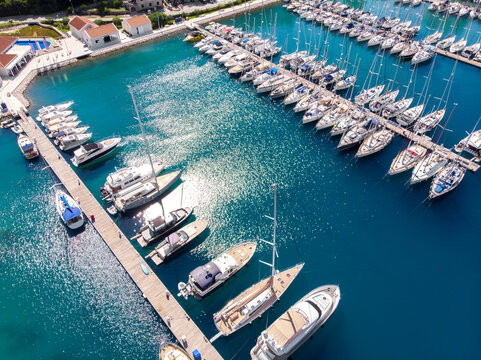 Scenic aerial view many yacht boats moored at Croatian bay harbor shore blue turquoise clear water at bright summer sunny day. Top above Mediterranean sea marina. Boat vessel charter service