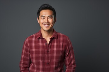 Obraz premium Portrait of a content asian man in his 30s wearing a comfy flannel shirt isolated in soft gray background
