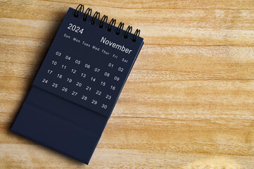 Top view of November 2024 black desk calendar on wooden table background