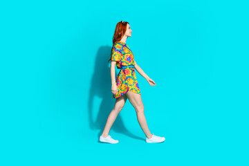 Full length photo of lovely young lady profile walking dressed stylish colorful garment isolated on cyan color background