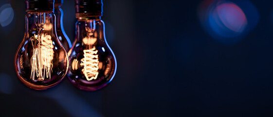 A burning lamps hangs in the dark on a blurred background. Space for text.