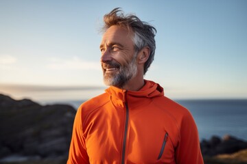 Portrait of a glad man in his 50s sporting a technical climbing shirt in serene seaside background