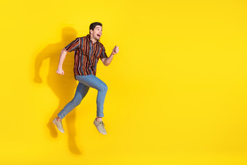 Full length portrait of nice young man jump run empty space wear shirt isolated on yellow color background