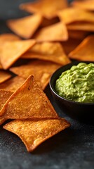 Crunchy tortilla chips served with creamy guacamole in a black bowl.