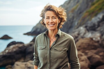 Portrait of a glad woman in her 50s sporting a breathable hiking shirt isolated in rocky shoreline background