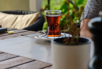 A serene afternoon tea in a garden cafe overlooking lush greenery with a glass of aromatic brew on the table