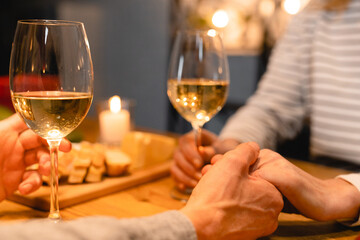 Close up cropped photo of lover`s hands on the romantic date with wine and food. I love you. Proposal of heart. Togetherness and relationship.