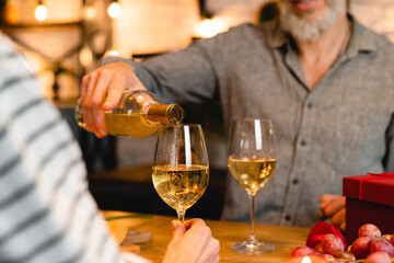 Cropped shot of a happy couple pouring wine into glasses during romantic date for cheering toasting clinking celebration of special event, Christmas, anniversary, engagement, Valentine`s Day - Powered by Adobe