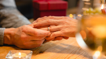 Close up photo of couple`s hands with engagement ring during romantic date. Wedding, proposal of heart, she said yes concept. Gift receiving - love language. Present for Valentine`s day