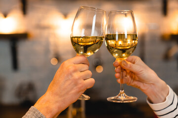 Close up photo of clinking glasses with wine on a romantic date. Cheering toasting, making wishes on anniversary, Christmas, Valentine`s Day