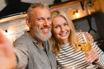 Happy married couple taking selfie while on a romantic date in the kitchen. Husband and wife, spouses, girlfriend and boyfriend streaming online on anniversary Valentine`s Day
