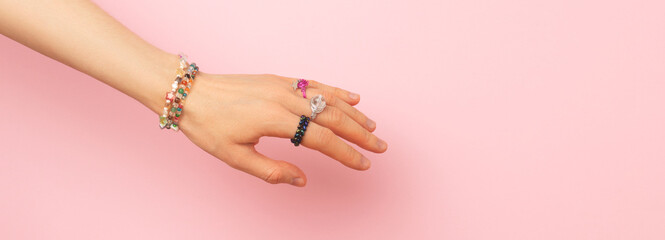 Banner with handmade rings and bracelets on a female hand in front of pink background. Place for text.