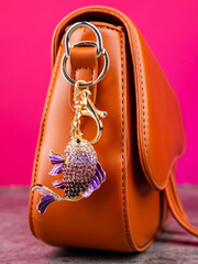 Close up of bright metal fish shaped rhinestone keychain on brown bag