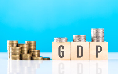 Wooden block labeled 'GDP' alongside a stack of coins. Symbolizes economic growth, emphasizing the significance of Gross Domestic Product in assessing financial progress and national prosperity
