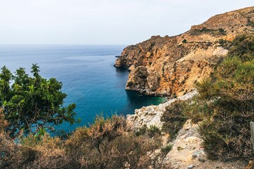 coastal view of rocky cliffs and  blue sea with lush vegetation in Andalusian Granada in Spain