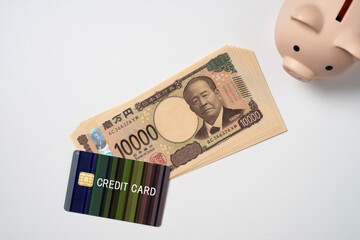クレジットカードと一万円札と豚の貯金箱