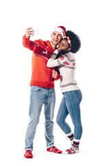 A happy couple embraces winter joy while taking a selfie in colorful holiday sweaters together.