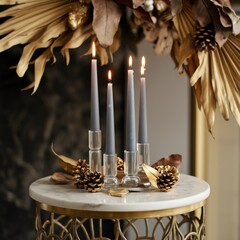 Elegant display of tall lit taper candles surrounded by gold pineapples and moody dried palm decorations on a contemporary marble table.