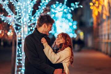 Obraz premium A romantic couple is hugging on a city street at new year's eve.
