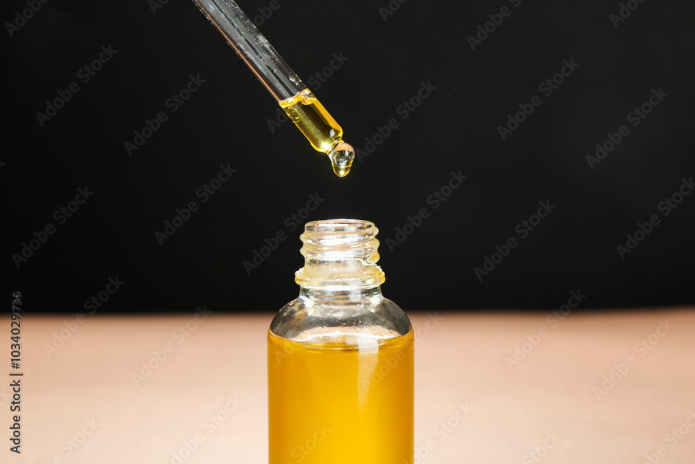 Wall mural Dripping tincture from pipette into bottle against color background, closeup