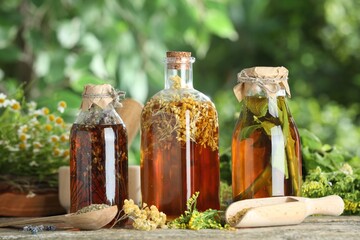 Different natural tinctures and herbs on wooden table outdoors