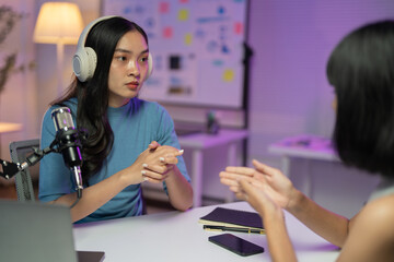 Two content creators are discussing the topic of their next podcast episode while sitting at a desk in a home recording studio