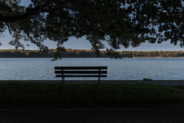 AUTUMN LANDSACAPE - A bench in park by lake under colorful leaves on a sunny day © Wojciech Wrzesień