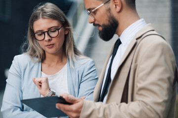 Business people having meeting while using digital tablet outdoors