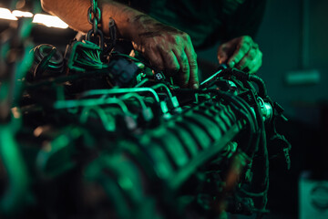 Focused mechanic with tools working on car engine in dim light.