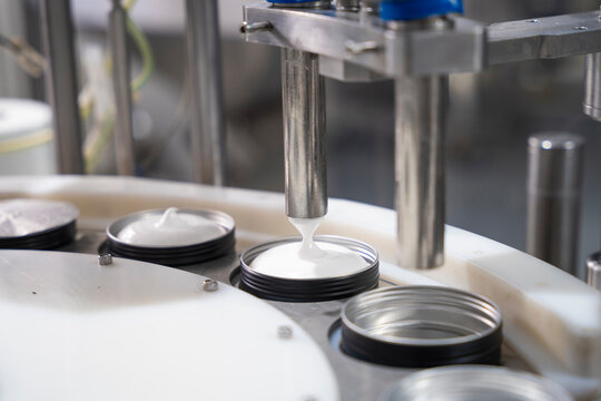 Production line of beauty and healthcare products at plant or factory. Process of manufacturing and packaging cosmetics goods, hand cream in metal container. Close up.