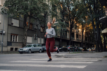 Young sporty woman running through the city during a day