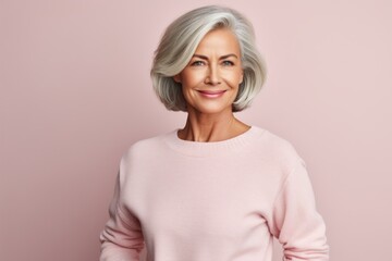 Obraz premium Portrait of a satisfied woman in her 60s wearing a cozy sweater in front of pastel or soft colors background