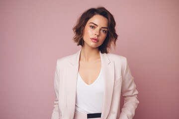 Obraz premium Portrait of a content woman in her 20s dressed in a stylish blazer in pastel or soft colors background