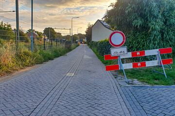 Provincial street with traffic sign prohibiting entry and circulation of vehicles, only bicycles and mopeds, cargo truck in background, summer sunset in Beek, South Limburg, Netherlands