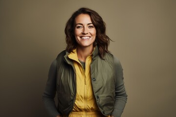Fototapeta premium Portrait of a happy woman in her 30s dressed in a water-resistant gilet isolated in minimalist or empty room background